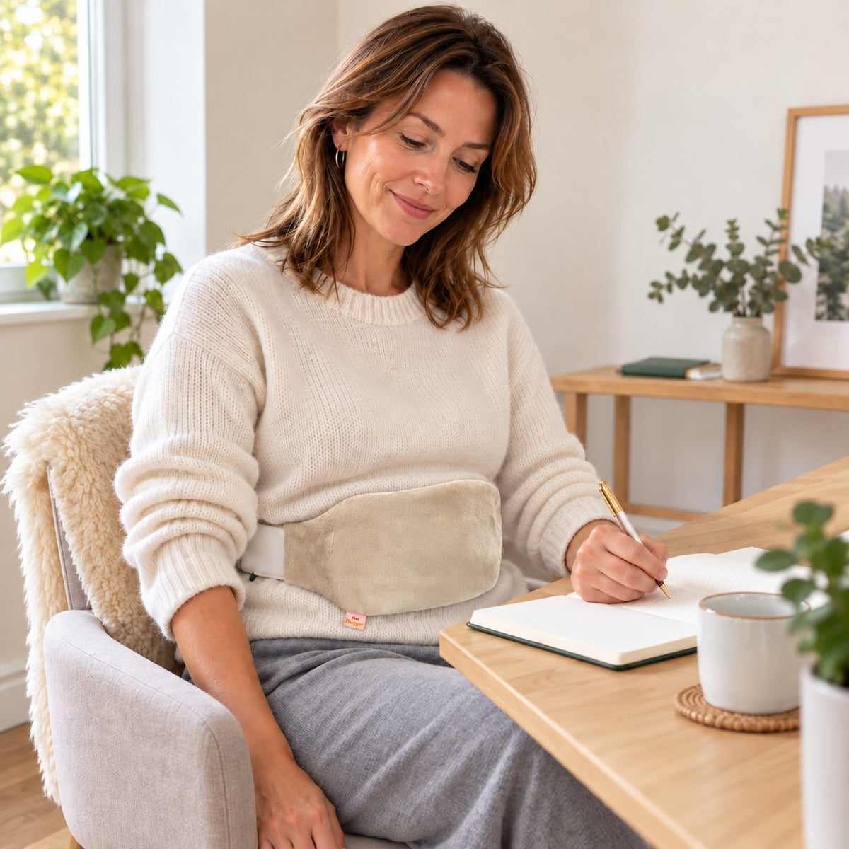 Woman writing at home with the Cream Hot Hugger cover fastened around her waist