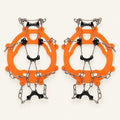 Orange adult chain ice grips with black underfoot plates and silver chains on warm ivory