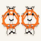 Orange adult chain ice grips with black underfoot plates and silver chains on warm ivory