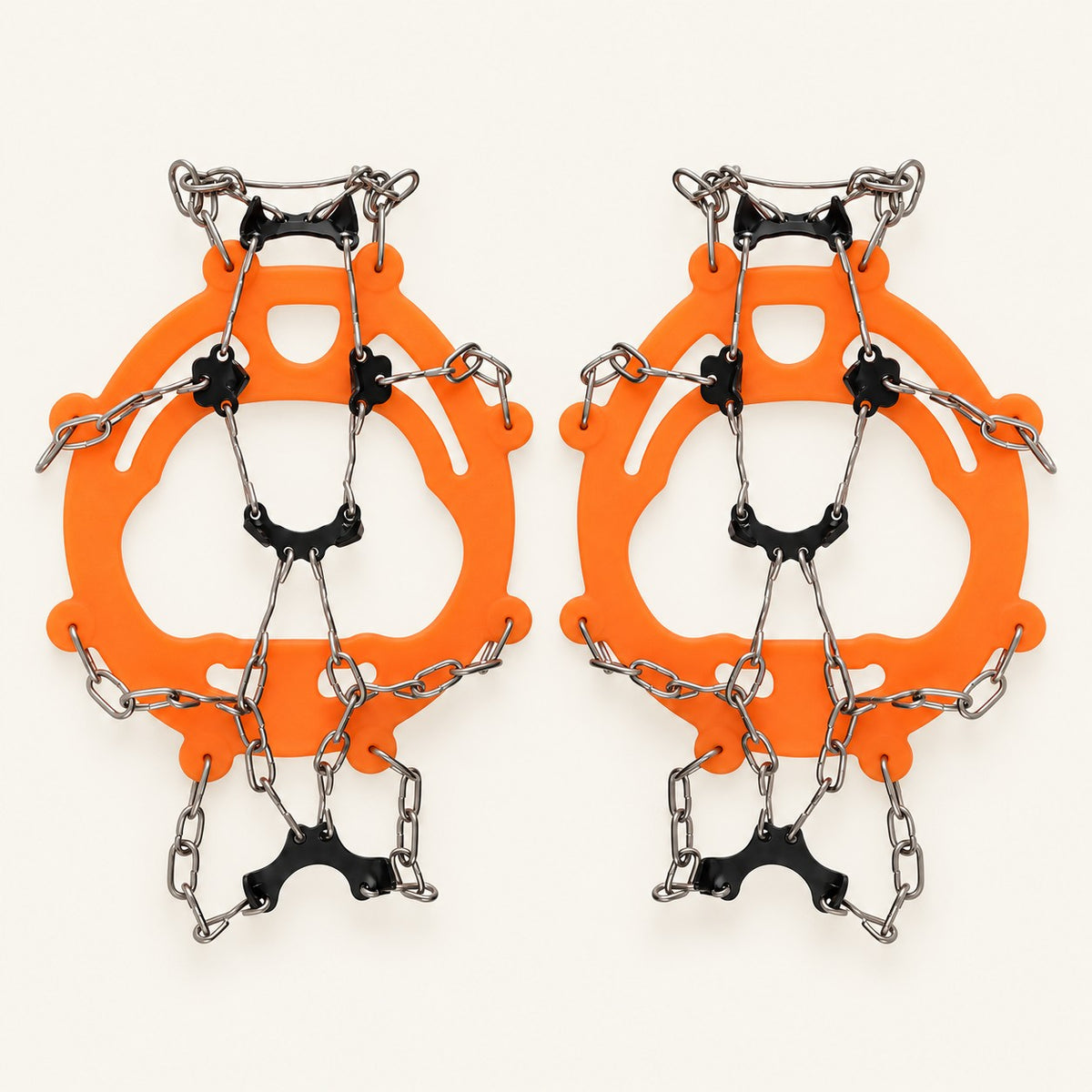 Orange adult chain ice grips with black underfoot plates and silver chains on warm ivory