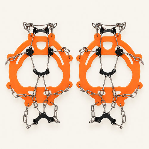 Orange adult chain ice grips with black underfoot plates and silver chains on warm ivory