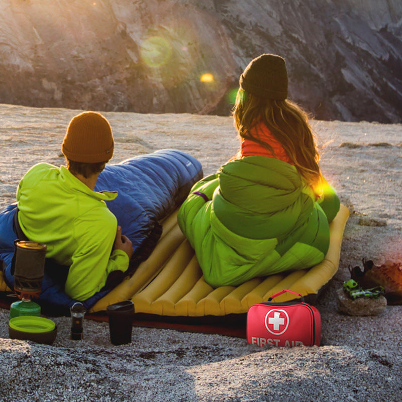 Portable red first aid kit beside campers at an outdoor campsite